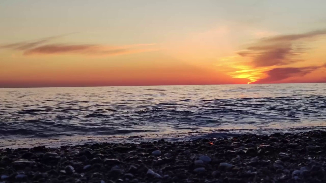 海水上的日落景色。黄昏时金色的太阳在五彩的天空中，海浪冲向海滩。在平稳循环的海洋上的奇妙日落。视频素材