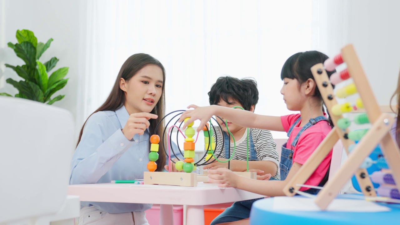 亚洲美丽的年轻女子老师在学校给孩子上课。魅力四射的女教师老师在幼稚园的课堂上用有趣的活动讲解和教育孩子们视频素材