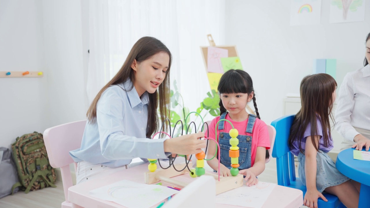 亚洲美丽的年轻女子老师在学校给孩子上课。魅力四射的女教师老师在幼稚园的课堂上用有趣的活动讲解和教育孩子们视频素材