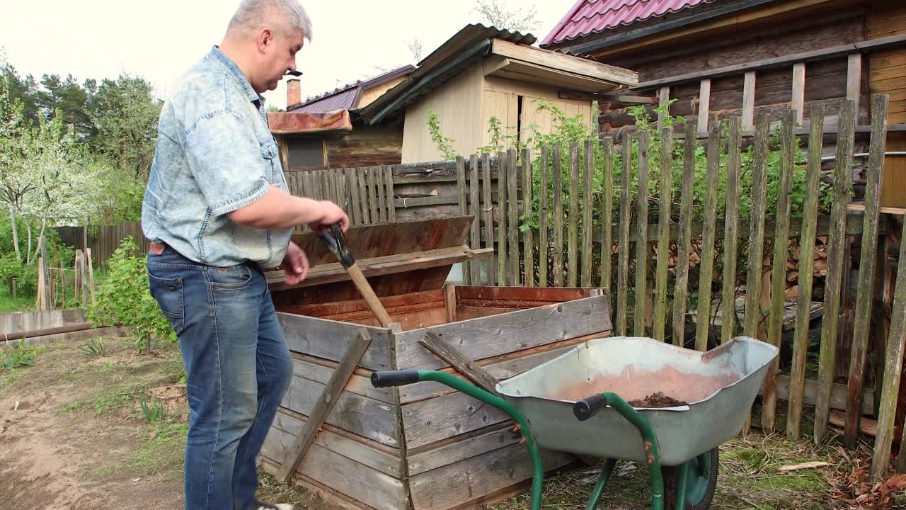 一个人用铲子把腐殖质或堆肥放进一辆车里。视频素材