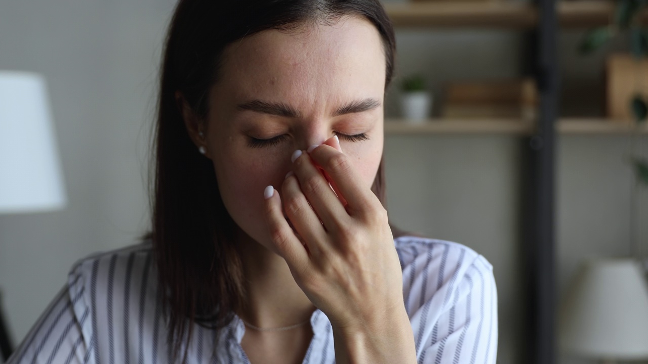 疲惫的女人觉得按摩鼻梁碰太阳穴不健康视频素材