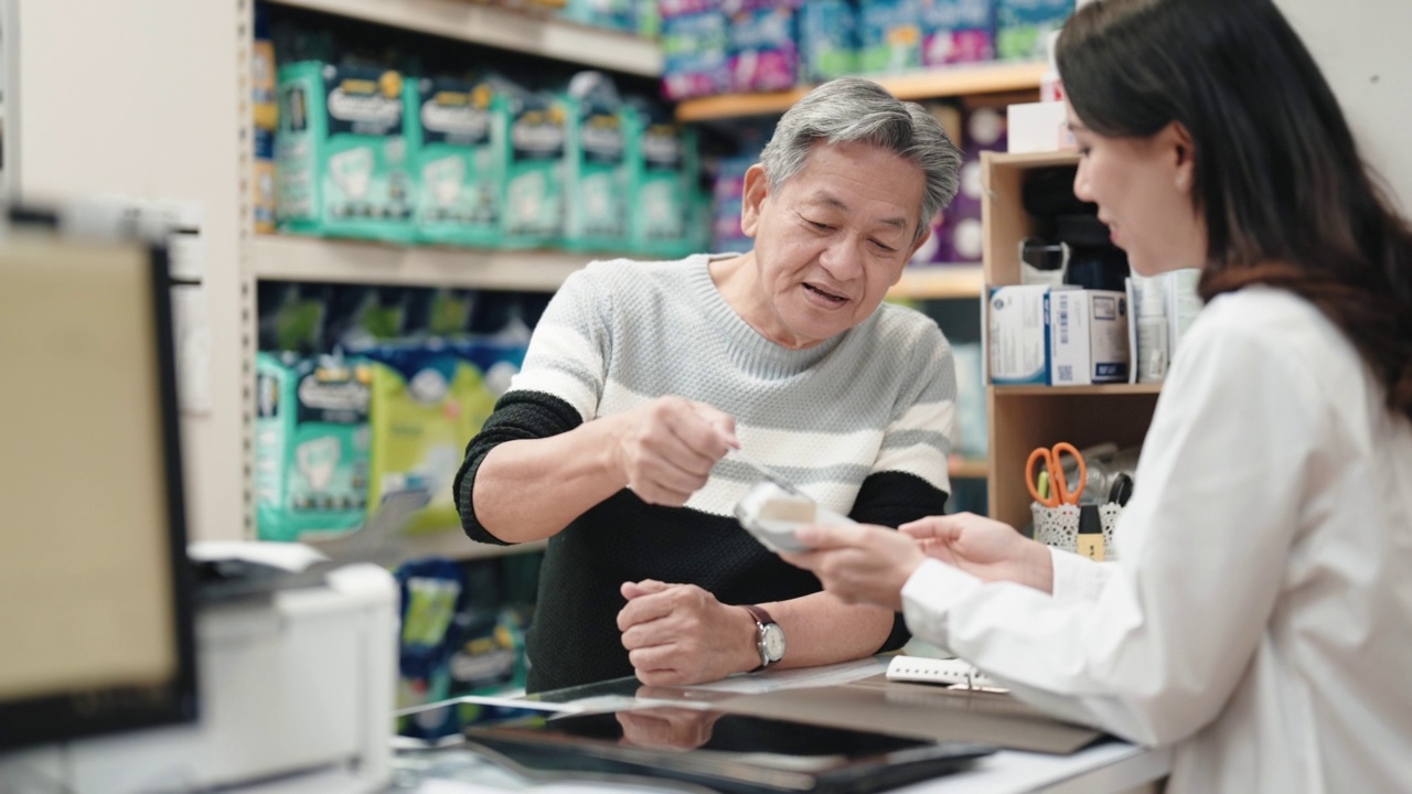 亚洲华人老人在药房柜台用信用卡支付非接触式支付视频素材