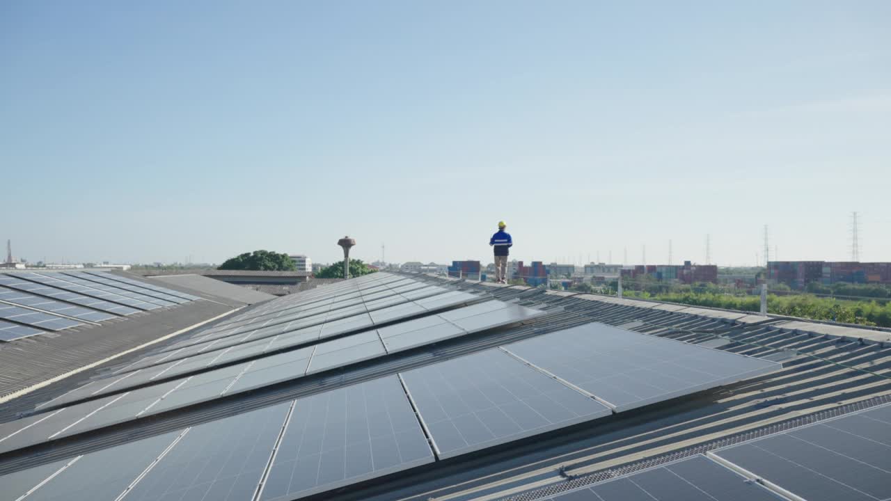 亚洲技术人员在屋顶工厂的光伏太阳能电池板背景场安装，检查或修理太阳能电池板。视频素材