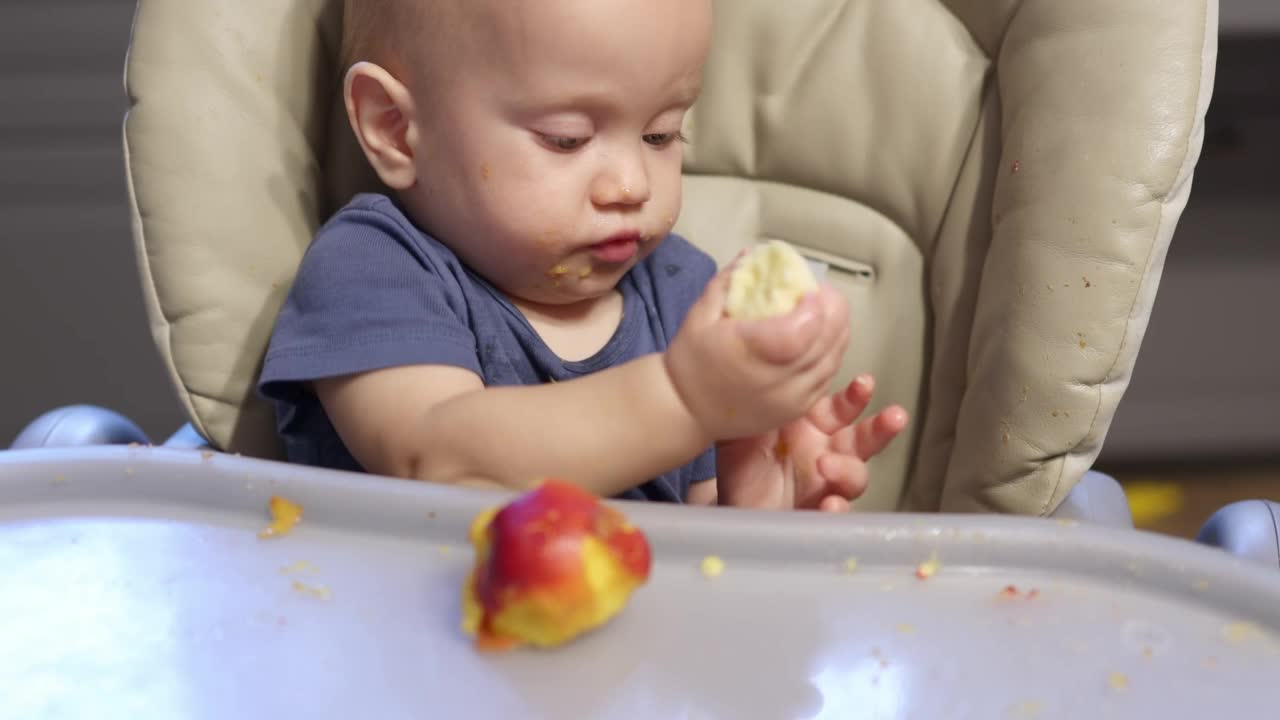 画像在家里吃婴儿水果。健康食品，午餐时间。孩子咬桃子视频素材