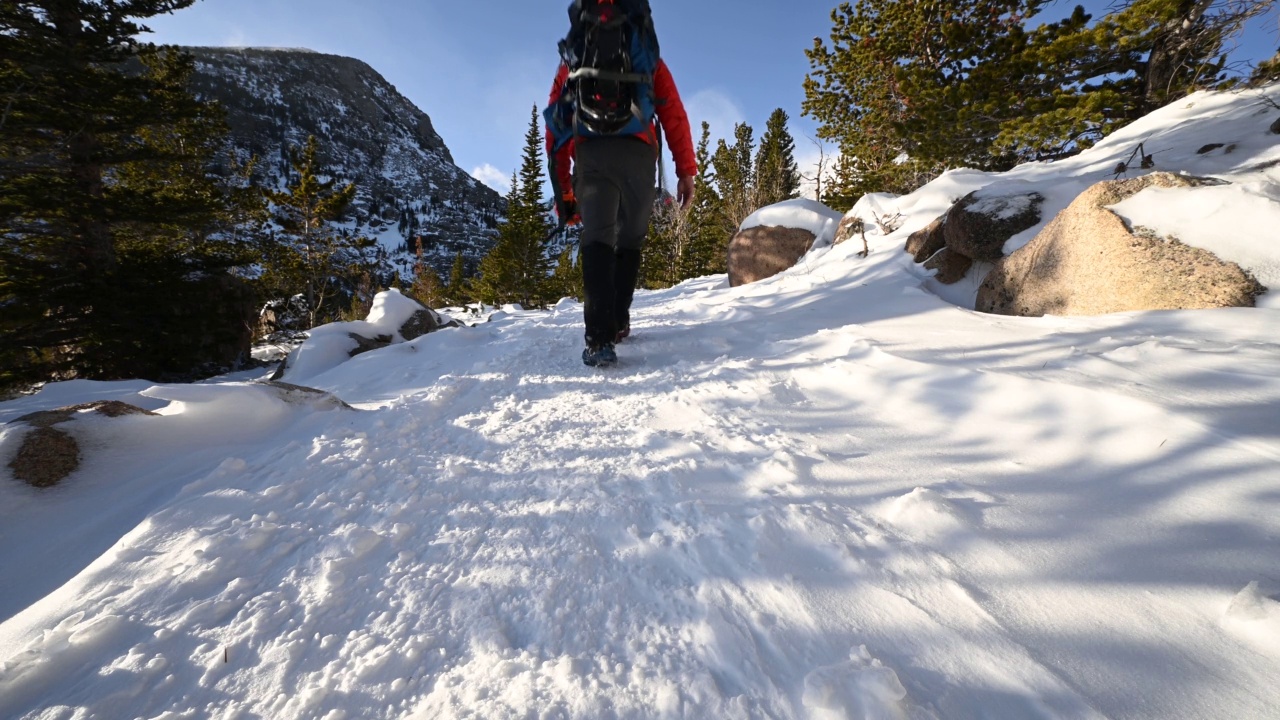 在美国科罗拉多州落基山国家公园的一条积雪覆盖的小道上徒步上山视频下载