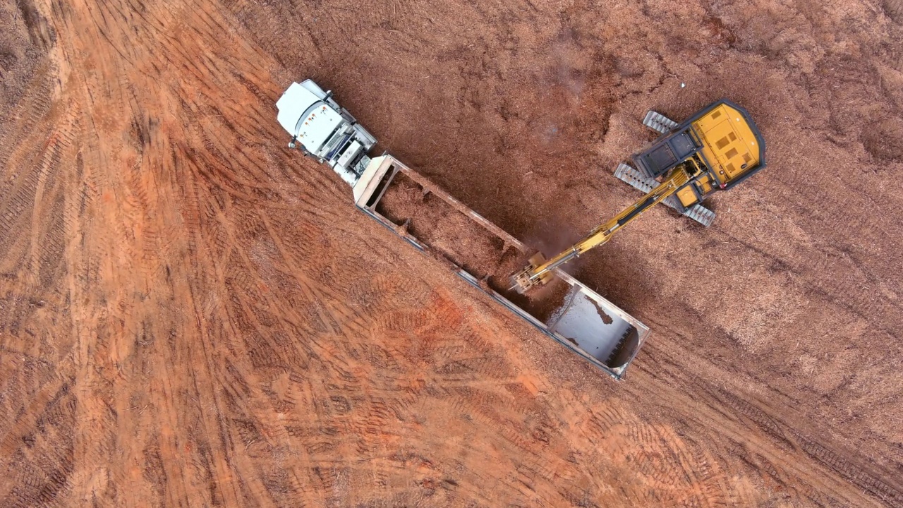 航拍的挖土机和卡车正在进行道路挖掘工程，把土搬到自卸卡车上视频素材