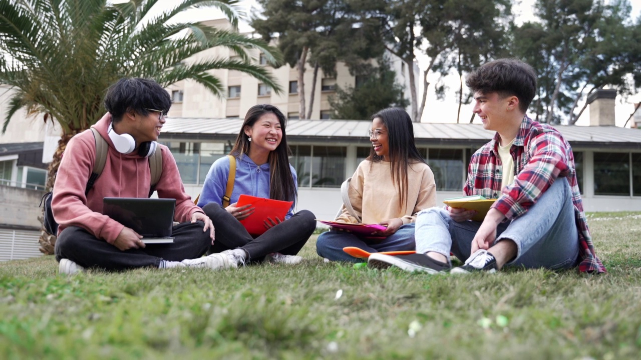 大学生朋友坐在草地上，聊天，分享在大学校园的时刻视频素材