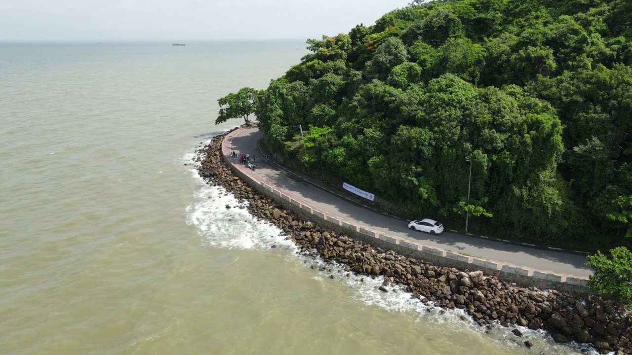 空中转弯轨道拍摄，揭示了一辆汽车行驶在曲线公路海滨视频素材