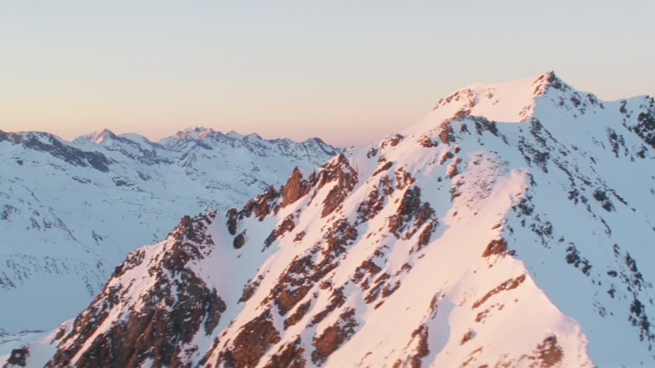 日出时雪山山脊映衬天空的鸟瞰图视频素材