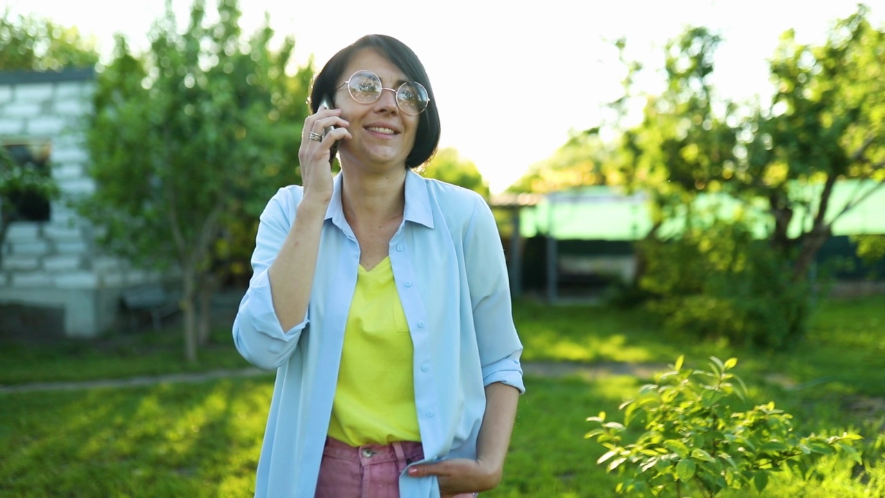 戴着眼镜的快乐女人在户外打手机，视频素材