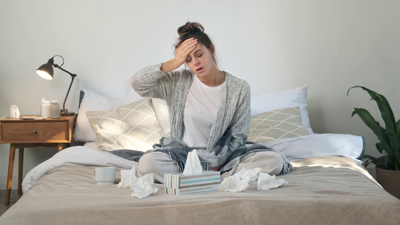 生病的年轻女子因流感和严重头痛而躺在床上。生病的女孩感到头痛。冬季感冒和流感的概念视频素材