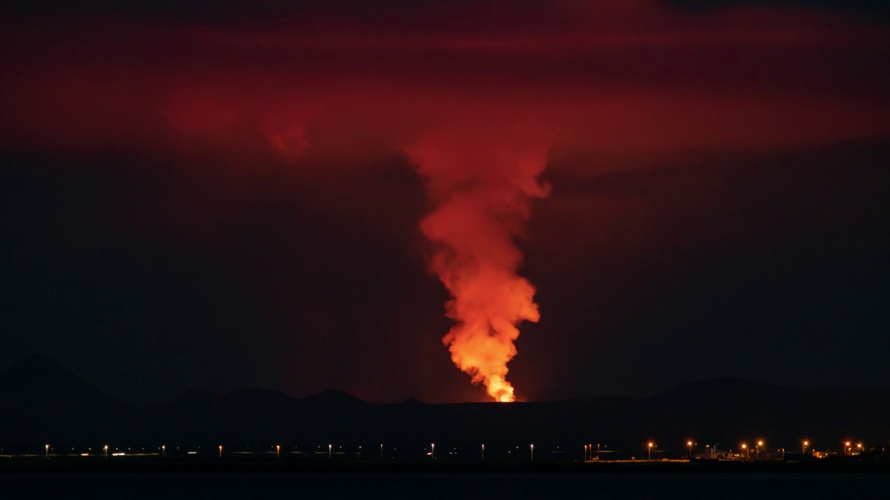 冰岛雷克雅未克的夜晚，火山在交通上空喷发出滚滚的红色烟雾视频素材