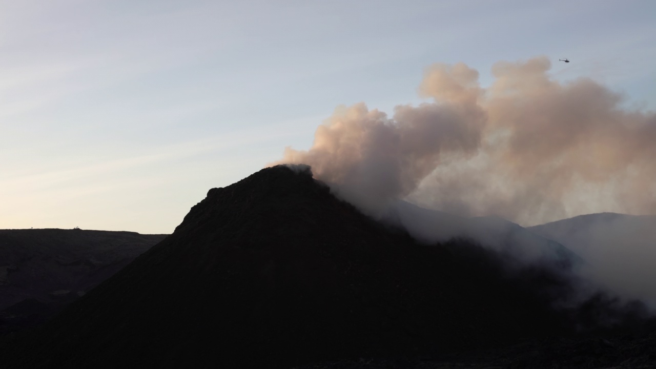 直升飞机飞过冰岛冒烟的火山锥视频素材