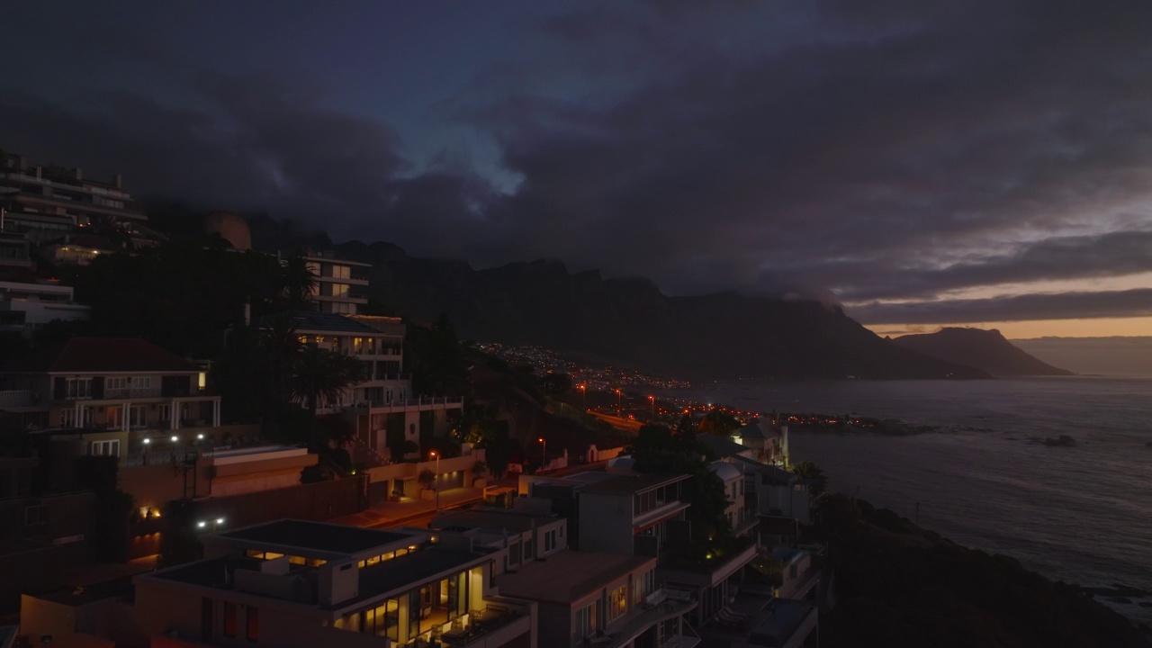 黄昏时海边的酒店或公寓。太阳落山后，向前飞行在城市居民区上空。开普敦，南非视频素材