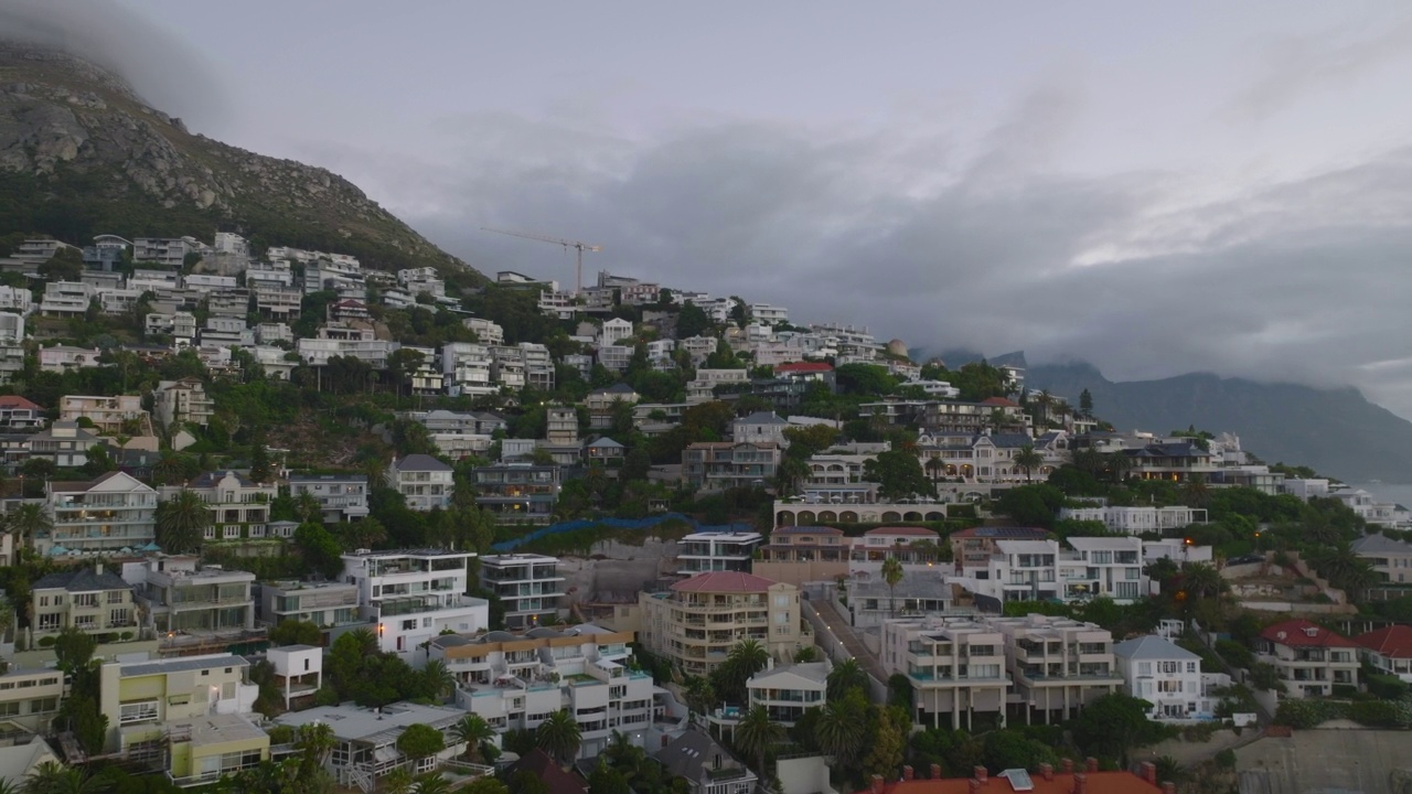 在靠近海岸的城市居民区的建筑物上向后飞行。黄昏时分的鸟瞰图。开普敦，南非视频素材