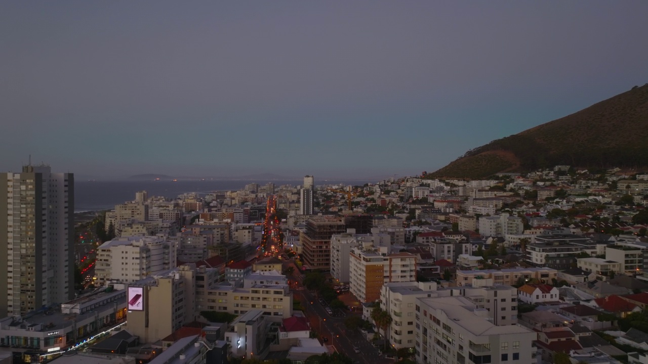 黄昏时分，向前飞在城市上空。背景是沿街和海边的多层公寓建筑。开普敦，南非视频素材