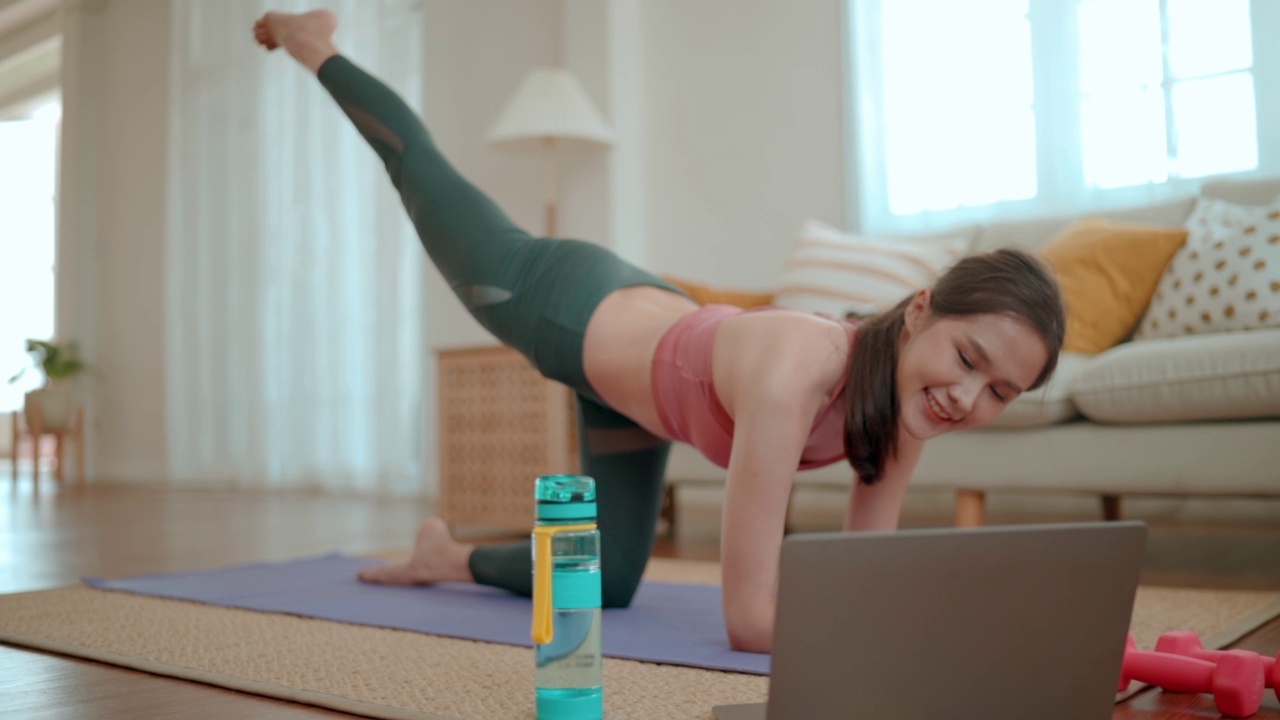 健康的少女在家用笔记本电脑在线练习瑜伽。视频素材
