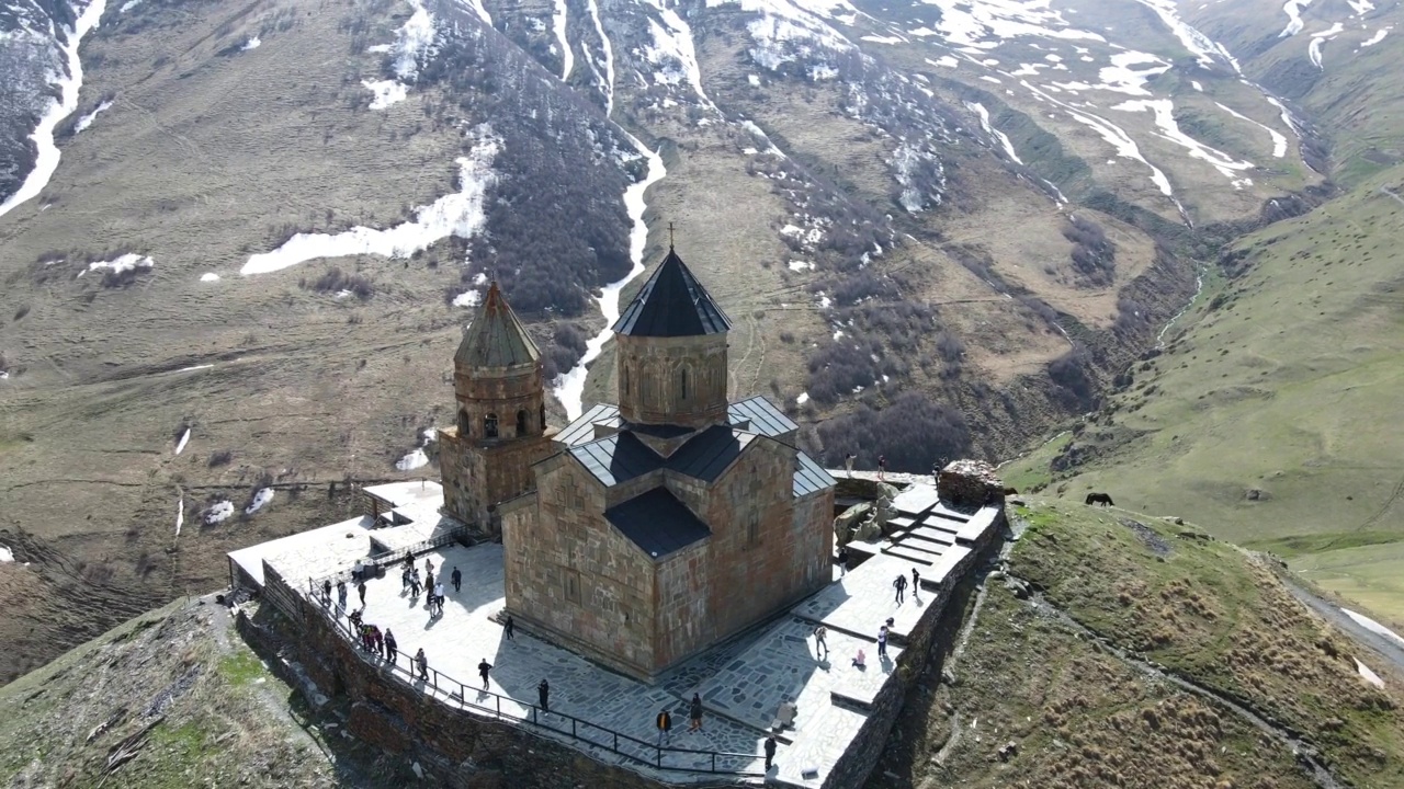 摄影无人机在乔治亚州Stepantsminda村附近的圣三一教堂(Gergeti Trinity Church)上空飞行视频素材