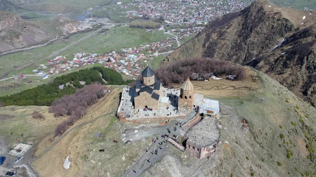 摄影无人机在乔治亚州Stepantsminda村附近的圣三一教堂(Gergeti Trinity Church)上空飞行视频素材