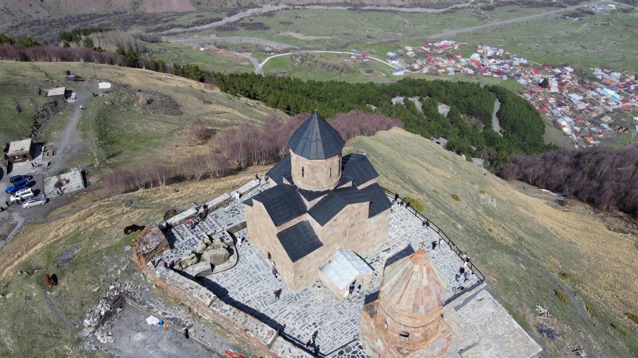 摄影无人机在圣三一教堂(Gergeti Trinity Church)上空盘旋，打开了斯Stepantsminda村的鸟瞰图视频素材