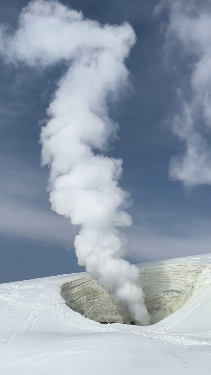 白雪皑皑的山腰上，火山烟雾从火山口上升视频素材