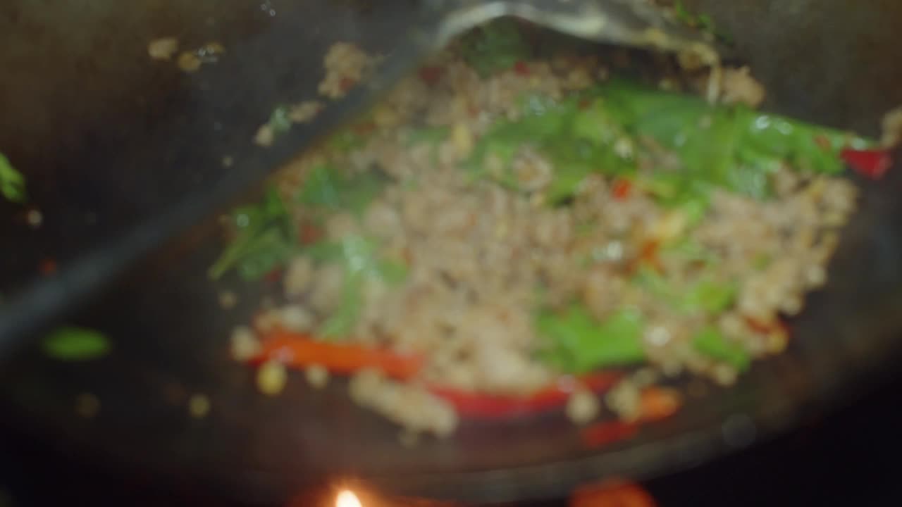 近距离的厨师烹饪辛辣的炒碎猪肉与泰国圣罗勒在煎锅，padkrapow是最受欢迎的泰国街头美食，泰国菜菜视频素材