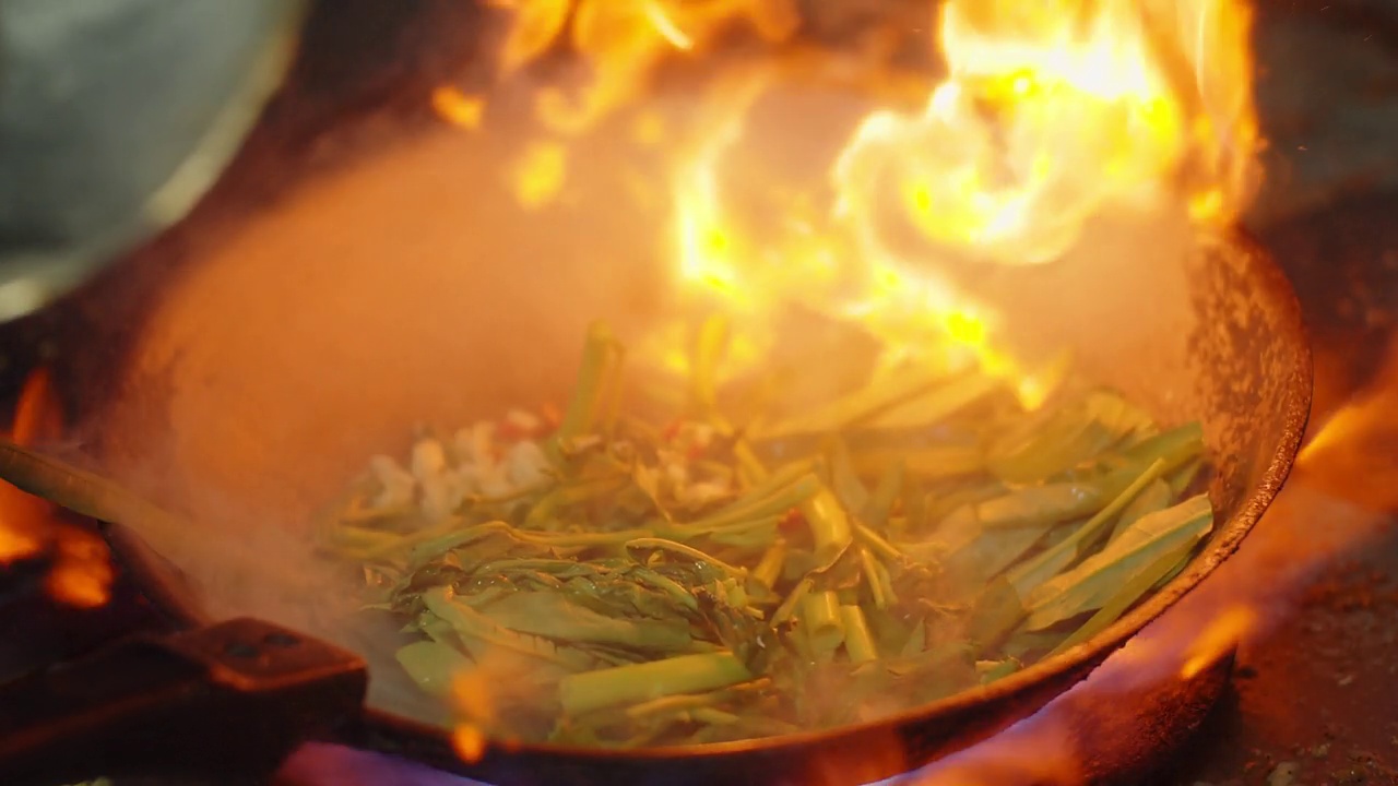 慢动作特写厨师烹饪炒锅蔬菜与食材和火焰，厨师烹饪泰国和中国风格的食物在厨房视频素材