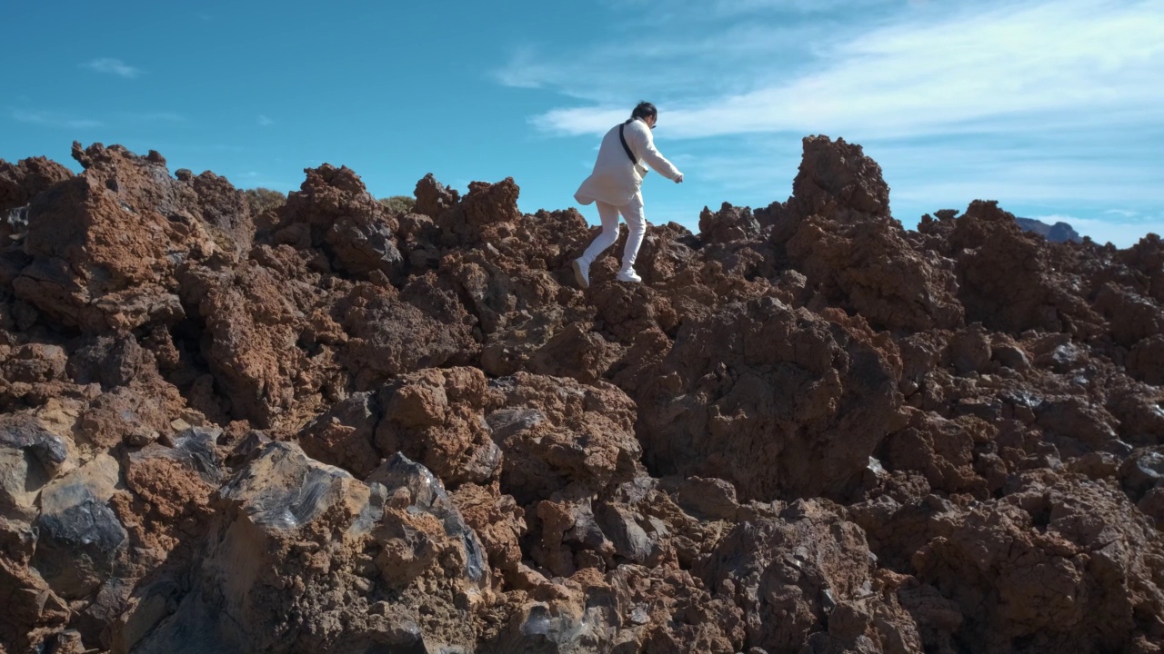 在特内里费岛的泰德火山国家公园里，一名女游客穿过凝固的熔岩山视频素材