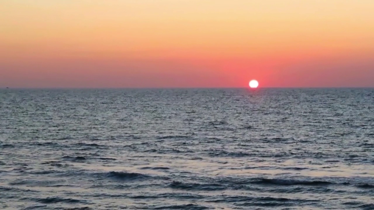 夏天的夕阳，太阳光线在橙粉色的天空上，平静的海水，海浪视频素材