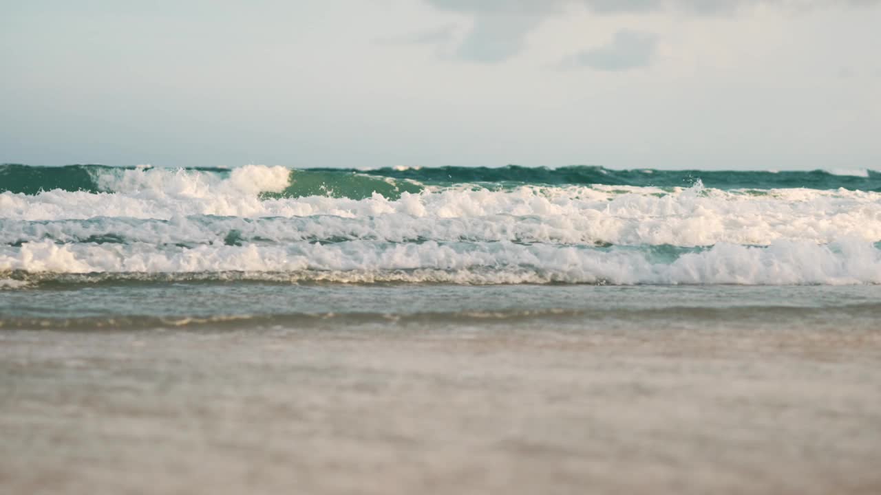 夏天的海滩、海沙和天空。海滩遇到深蓝色的海水和泡沫的波浪视频素材