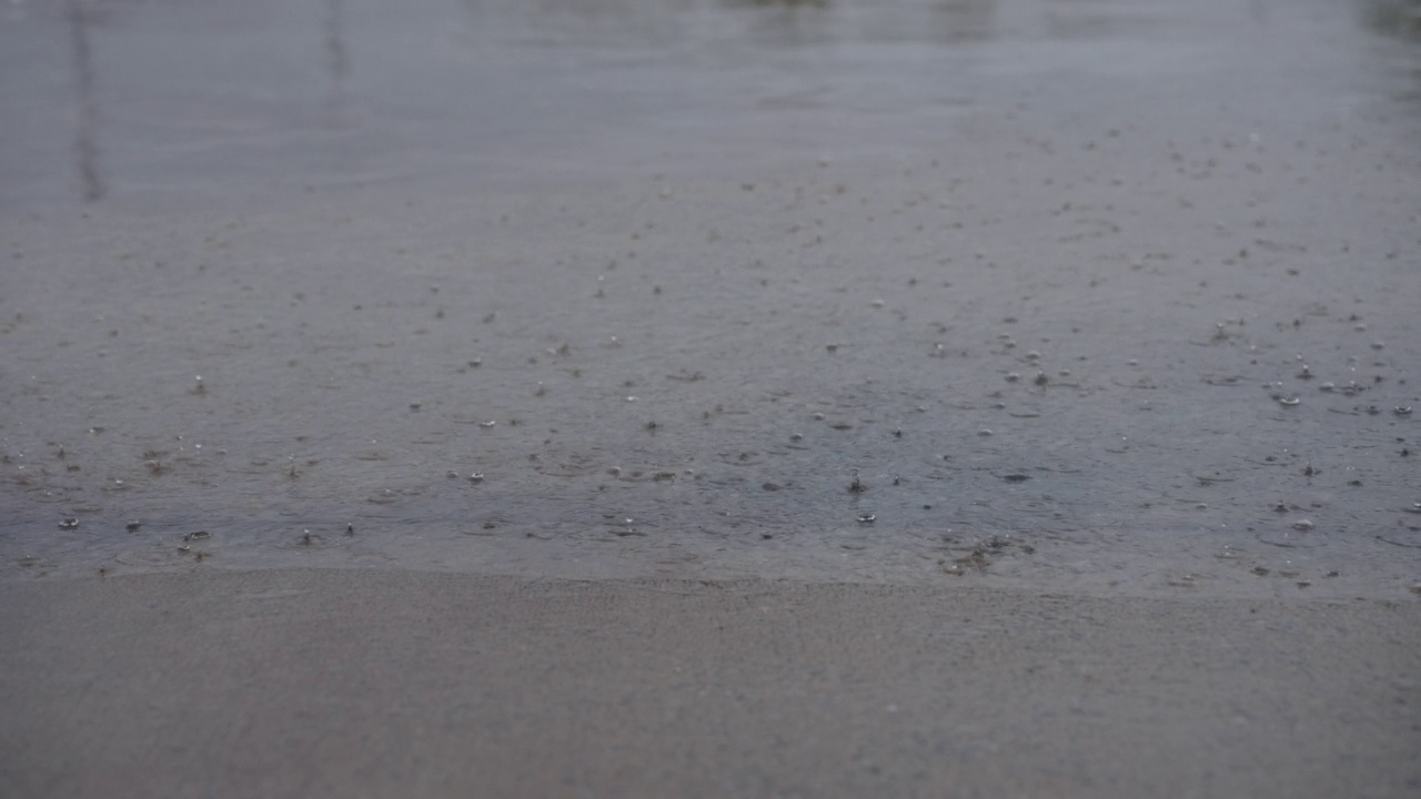 慢镜头，雨季的雨滴落在水泥地上。视频素材