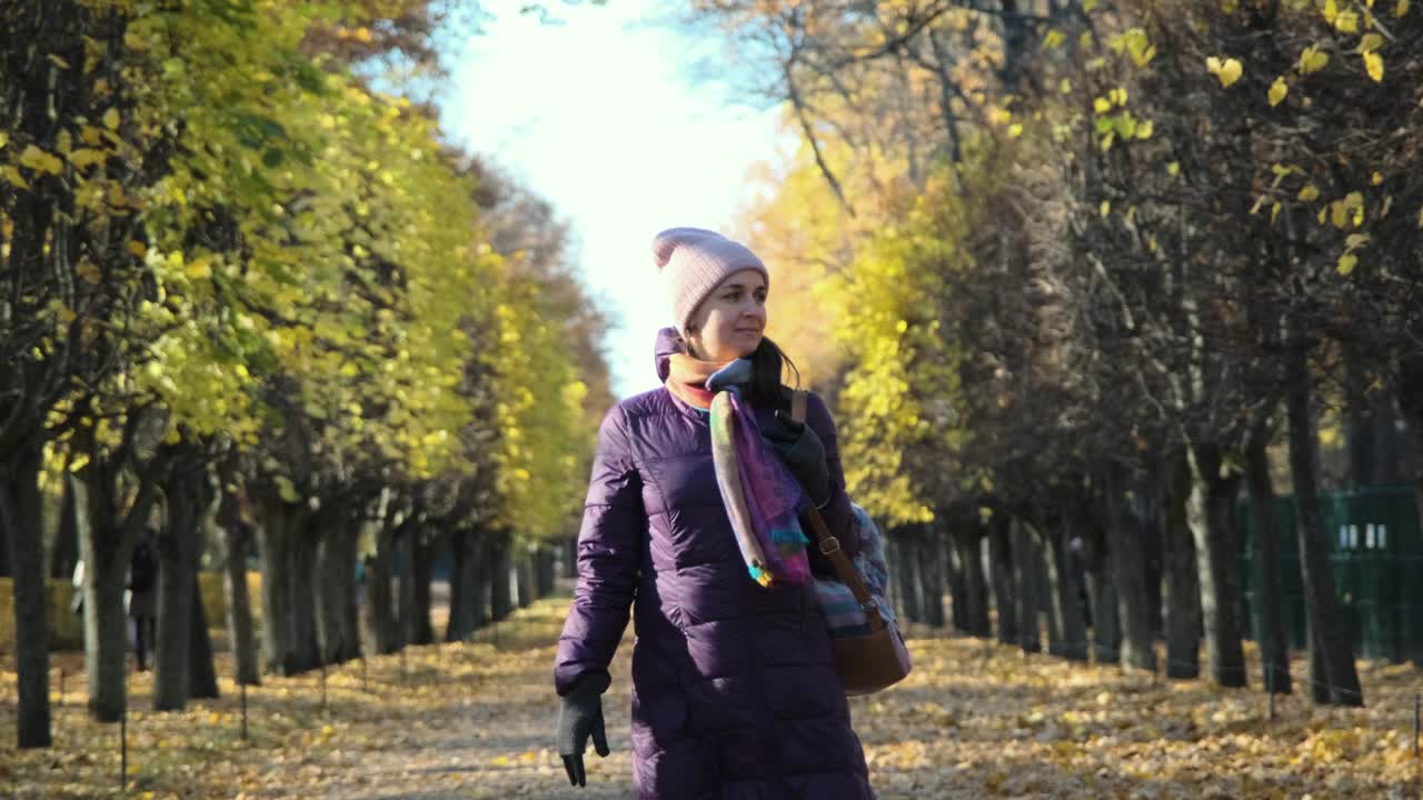 年轻美丽的女人走在秋天的公园里视频素材