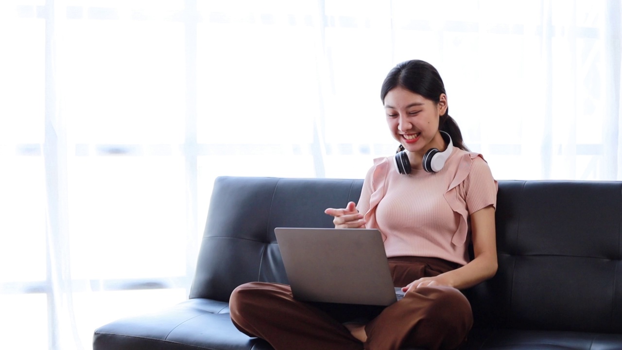 这位美丽的亚洲女子是一名大学生，她正在通过笔记本电脑与同学视频通话，讨论联合课程的小组作业。使用技术进行交流的概念。视频素材