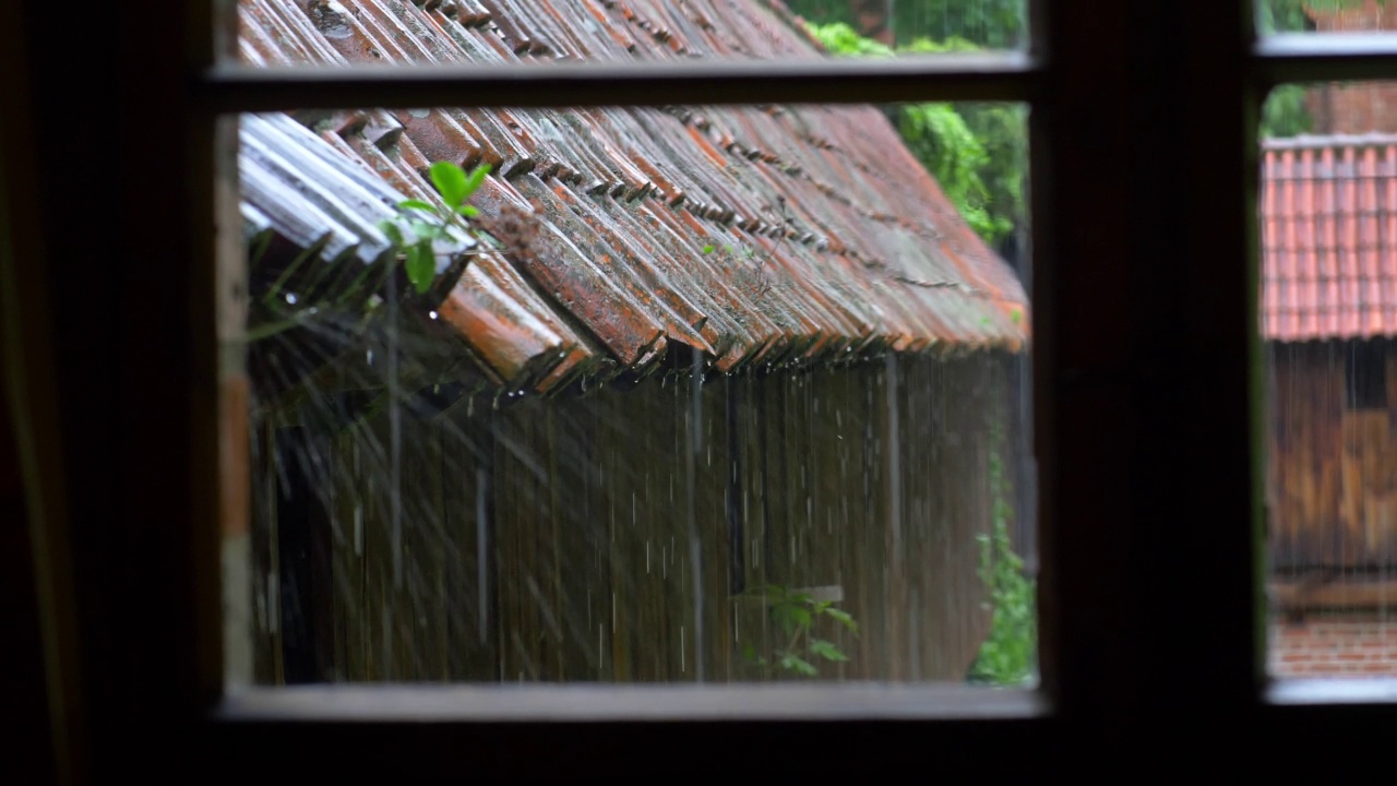 透过窗户看到雷雨中大雨打在老房子的屋顶瓦片上视频素材