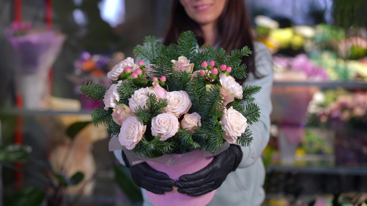 前视图不明女子站在花店伸展美丽的花束相机。苗条年轻的白人女花商在室内炫耀花卉。视频素材