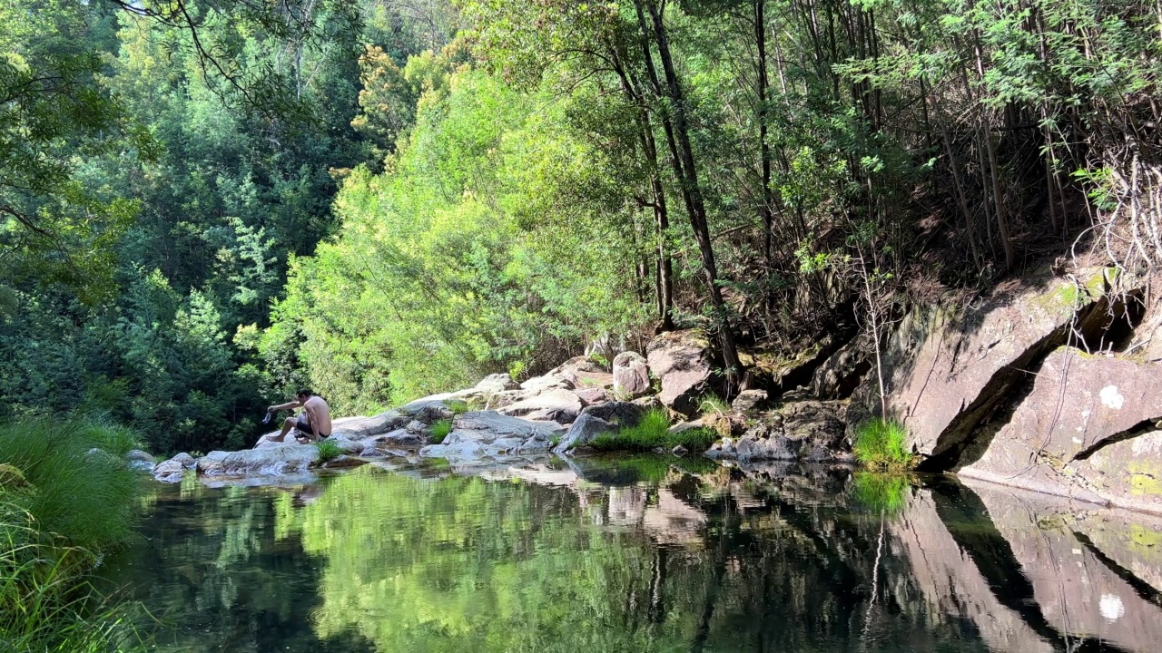 天堂的地方在丛林山湖，左边有一个瀑布，一个人到处游泳，绿色的树和透明的湖非凡的美丽，像从冒险电影。高质量的4 k视频素材