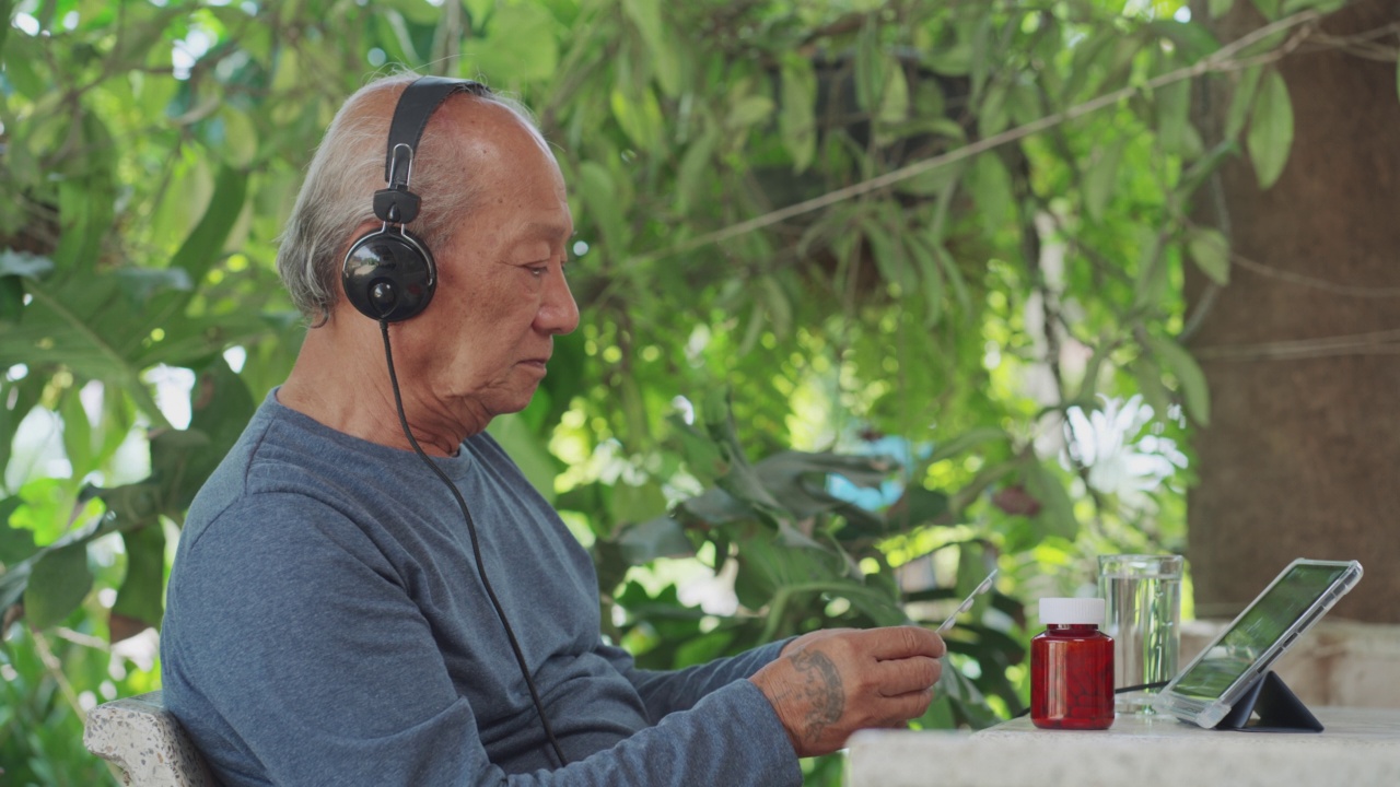 在家里的数字平板电脑上与医生进行远程医疗通话的老年男性，亚洲老年69岁视频素材