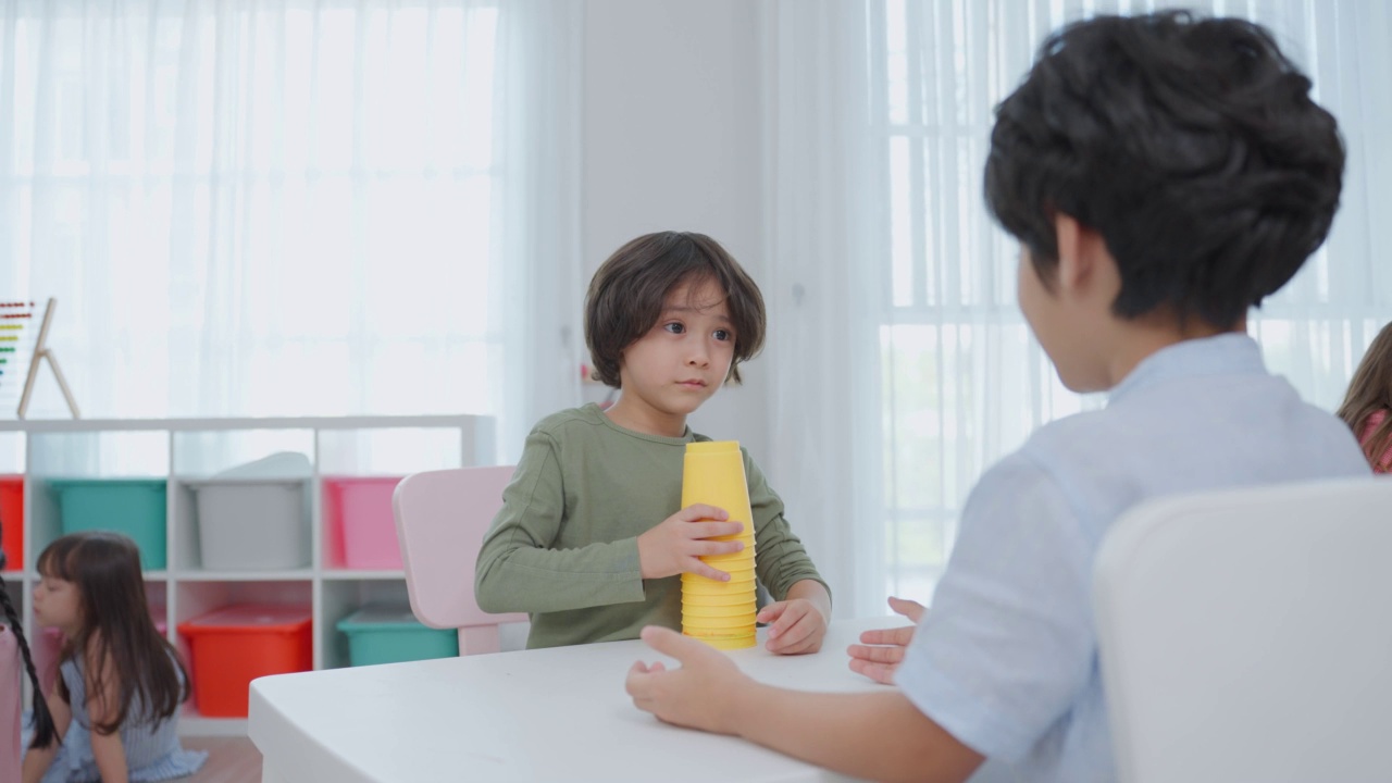 混血儿在学校一起玩耍的一群孩子。学龄前的小女孩和小男孩在幼儿园的教室里玩玩具时感到快乐和有趣。视频素材