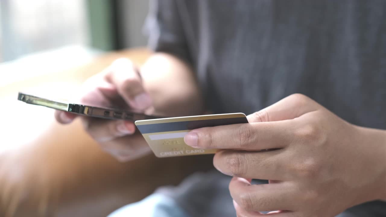 男子手持信用卡在手机上网购的特写，4K分辨率视频素材