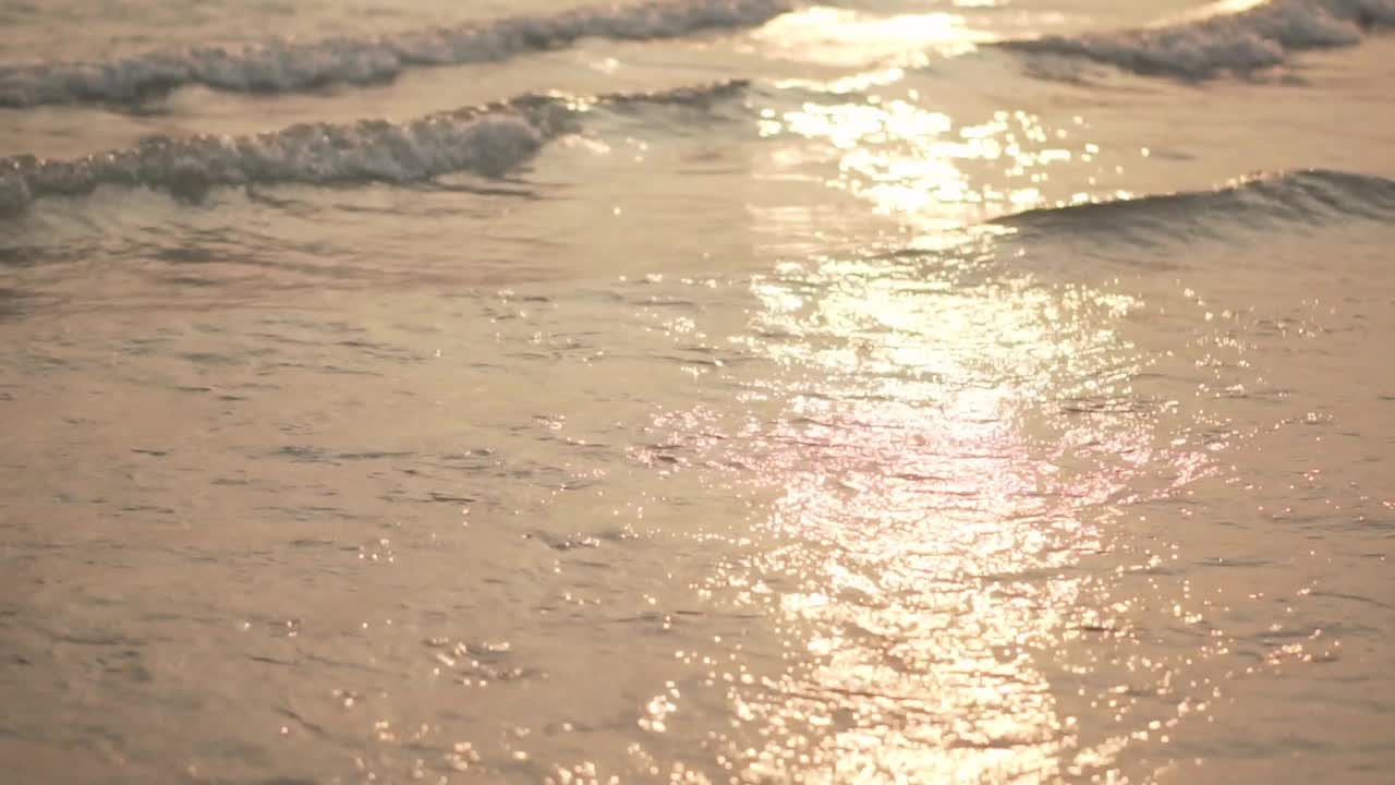 海浪慢慢地打到海滩上时，阳光在海面上的反射。慢动作视频素材