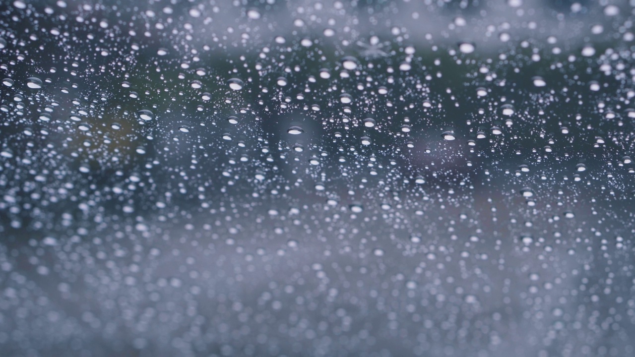 水滴在透明的玻璃背景下流下。孤立的雨滴，4K的视频，外面的暴雨，倾盆大雨。视频素材