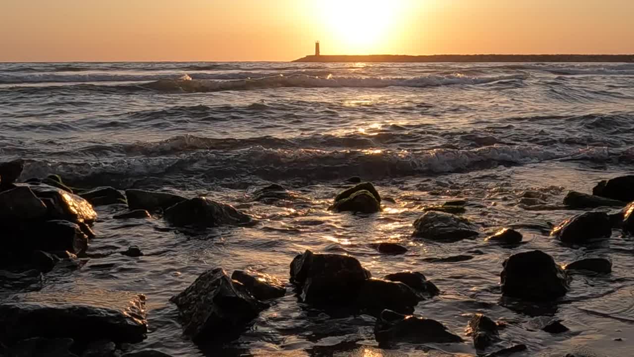 慢动作拍摄海浪，岩石与灯塔的看法在日落视频素材