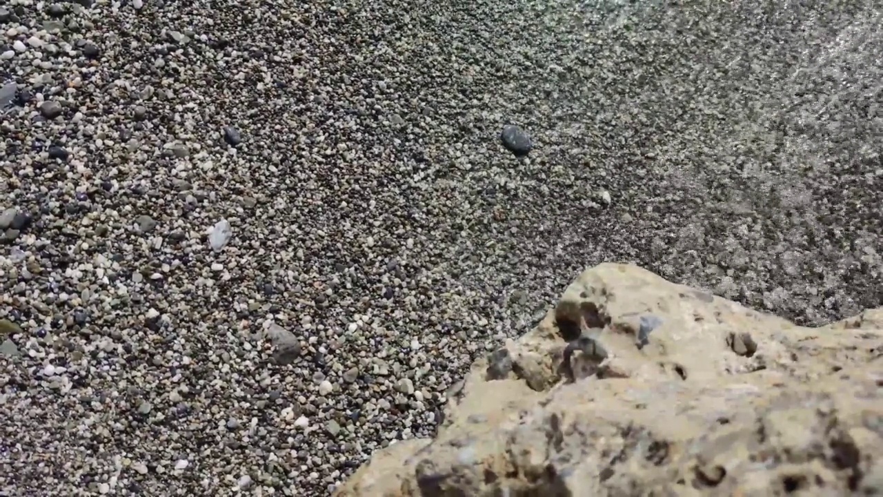 海浪卷起白色沙滩的特写镜头。水面纹理循环，阳光照射自然清澈碧蓝的水面。视频素材