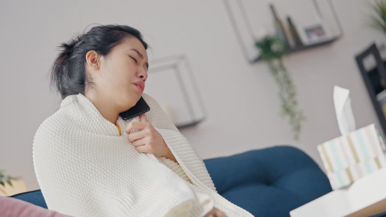 生病的女人一边打电话一边看体温计，用餐巾打喷嚏，流感视频素材