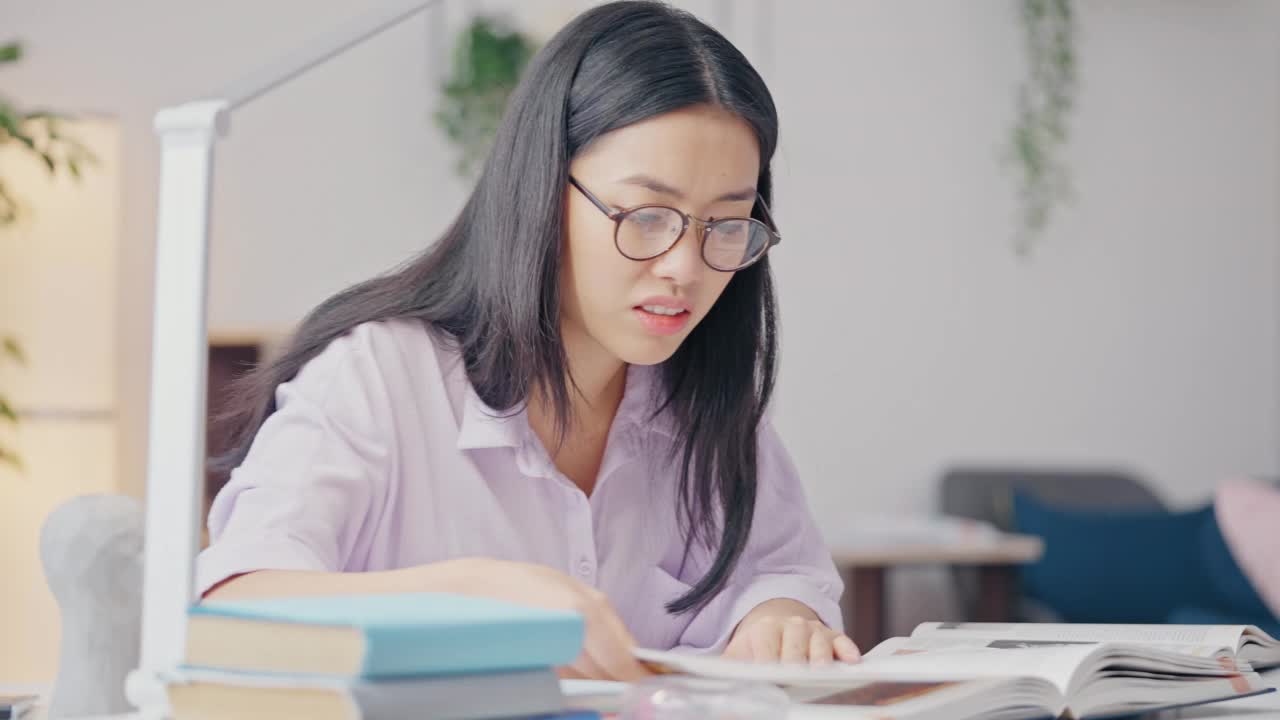 沮丧的亚洲女学生在家学习，翻着书视频素材