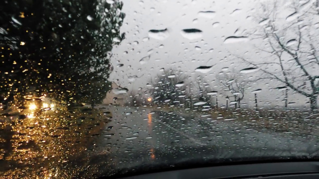 司机POV在雨中驾驶，挡风玻璃上有雨滴视频素材