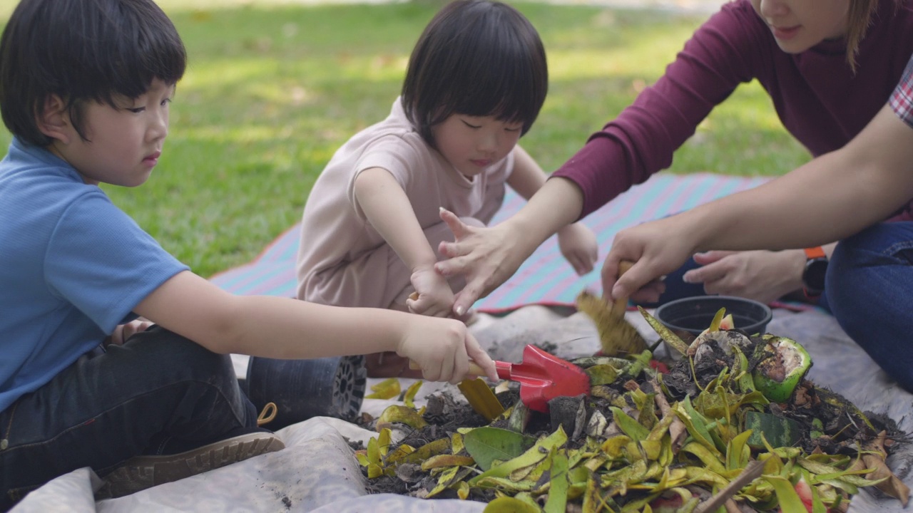 父亲和母亲教他们的两个儿子如何用厨房和花园的垃圾制作有机肥料视频素材