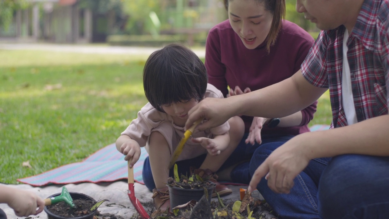 父亲和母亲教他们的两个儿子如何用厨房和花园的垃圾制作有机肥料视频素材