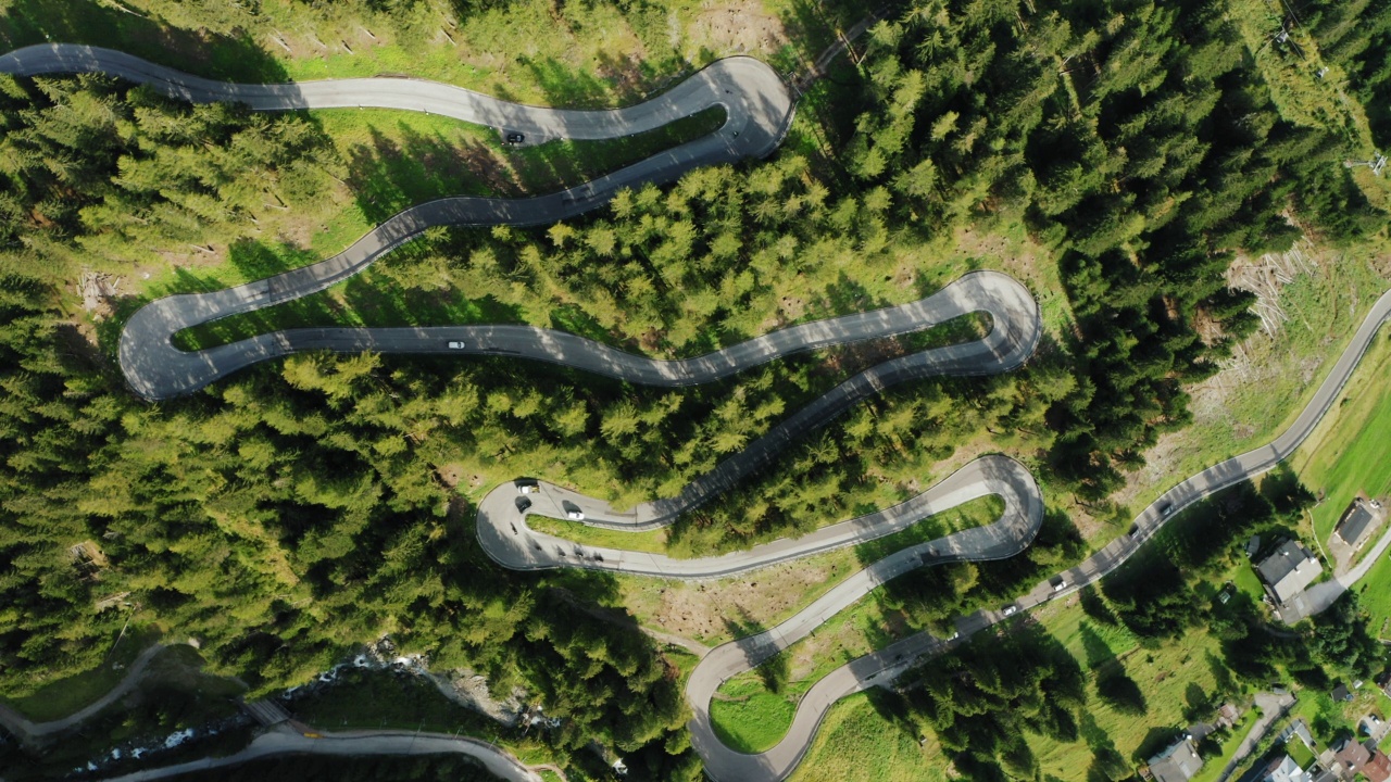 在意大利的Dolomites, Passo Giau附近，在树木之间的蜿蜒山路上的无人机俯瞰。许多弯道和汽车驶过。4 k的片段视频素材