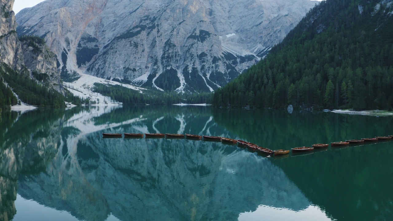 最美丽的Lago di Braies也被称为Pragser Wildsee。白云石山脉,意大利。飞出碧绿平静的水面，船在生涩。视频素材